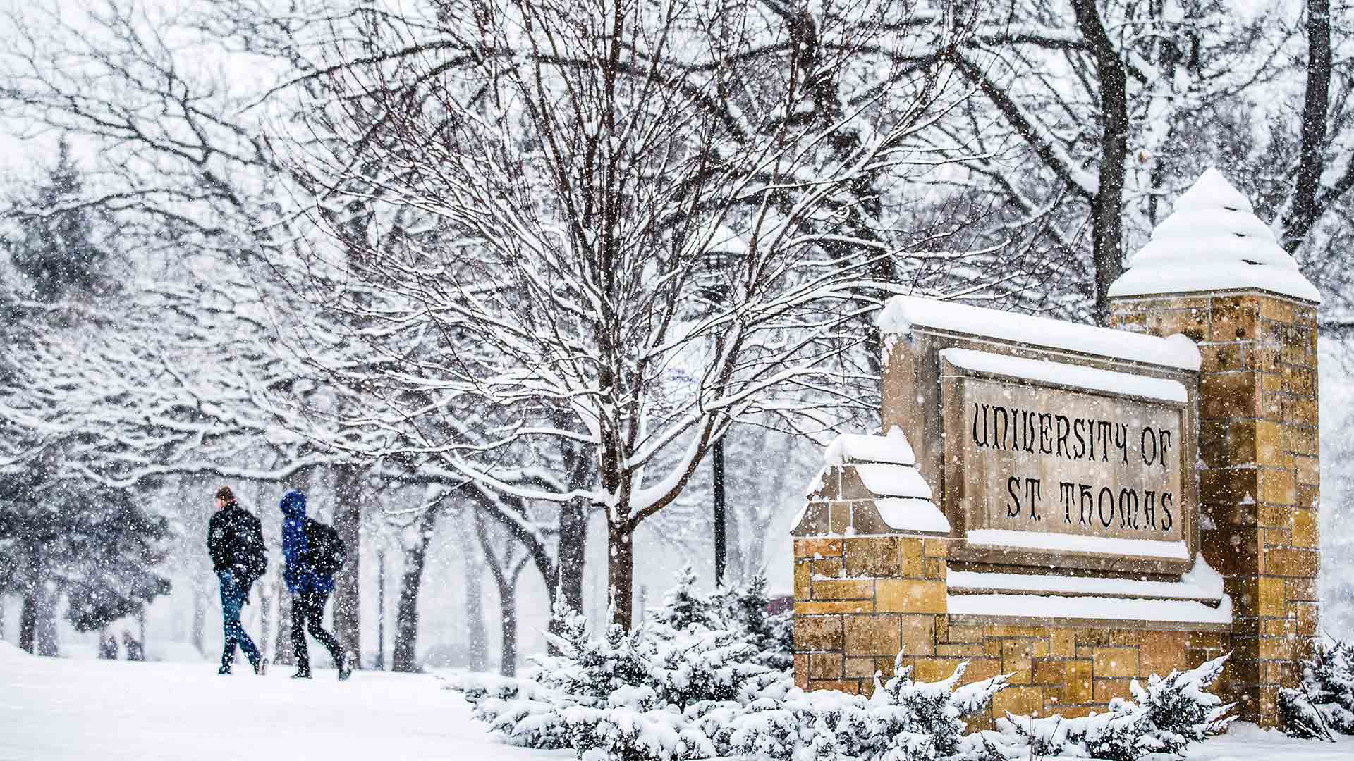 Stone University of St. Ҵý sign covered in falling snow.