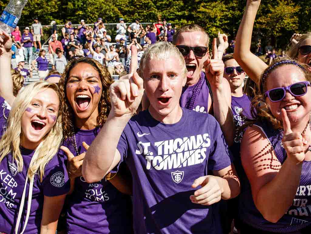 A group of students wearing purple St Ҵý Tommies shirts cheer for the camera