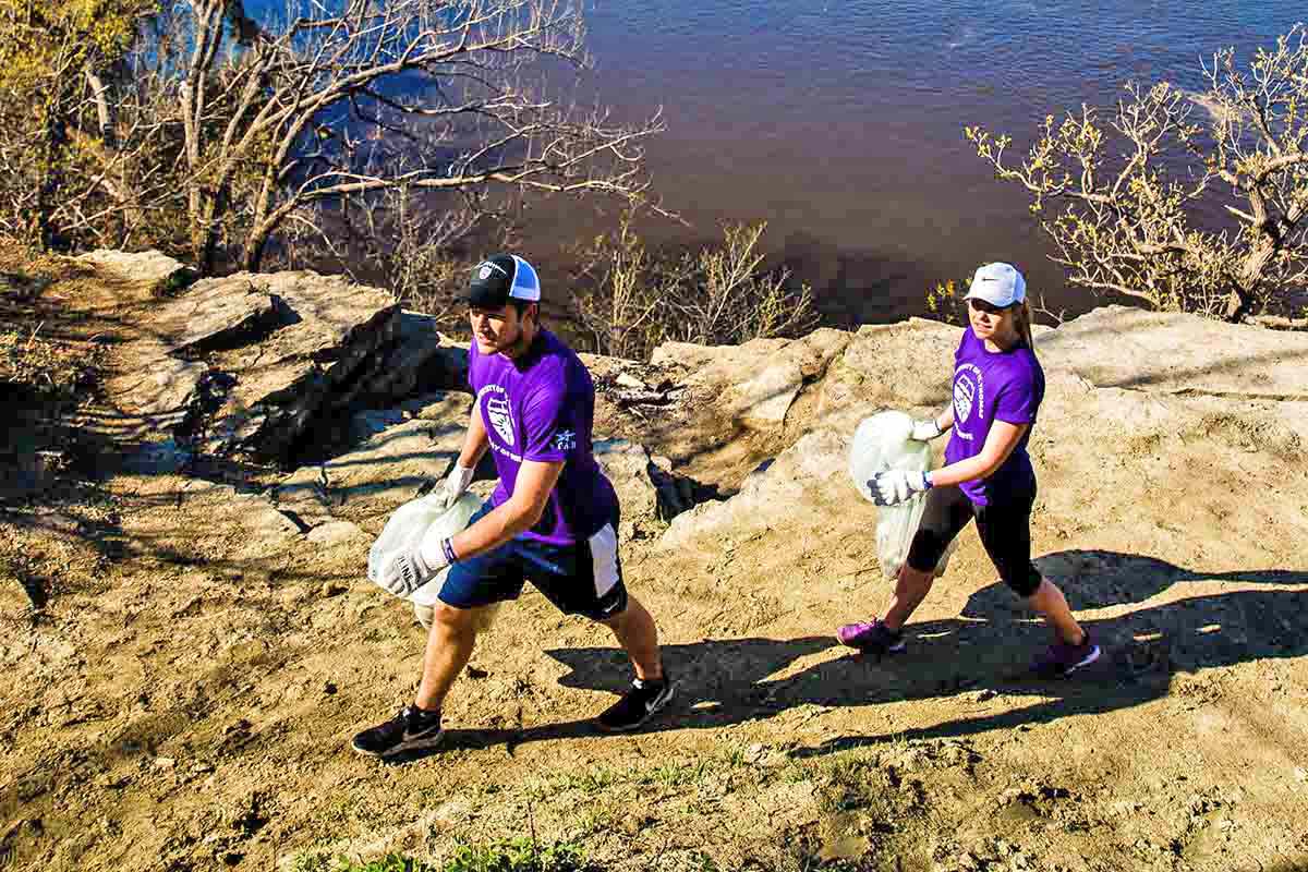 Students pick up trash along the shore of the Mississippi River in St. Paul during a St. Ҵý Day of Service.