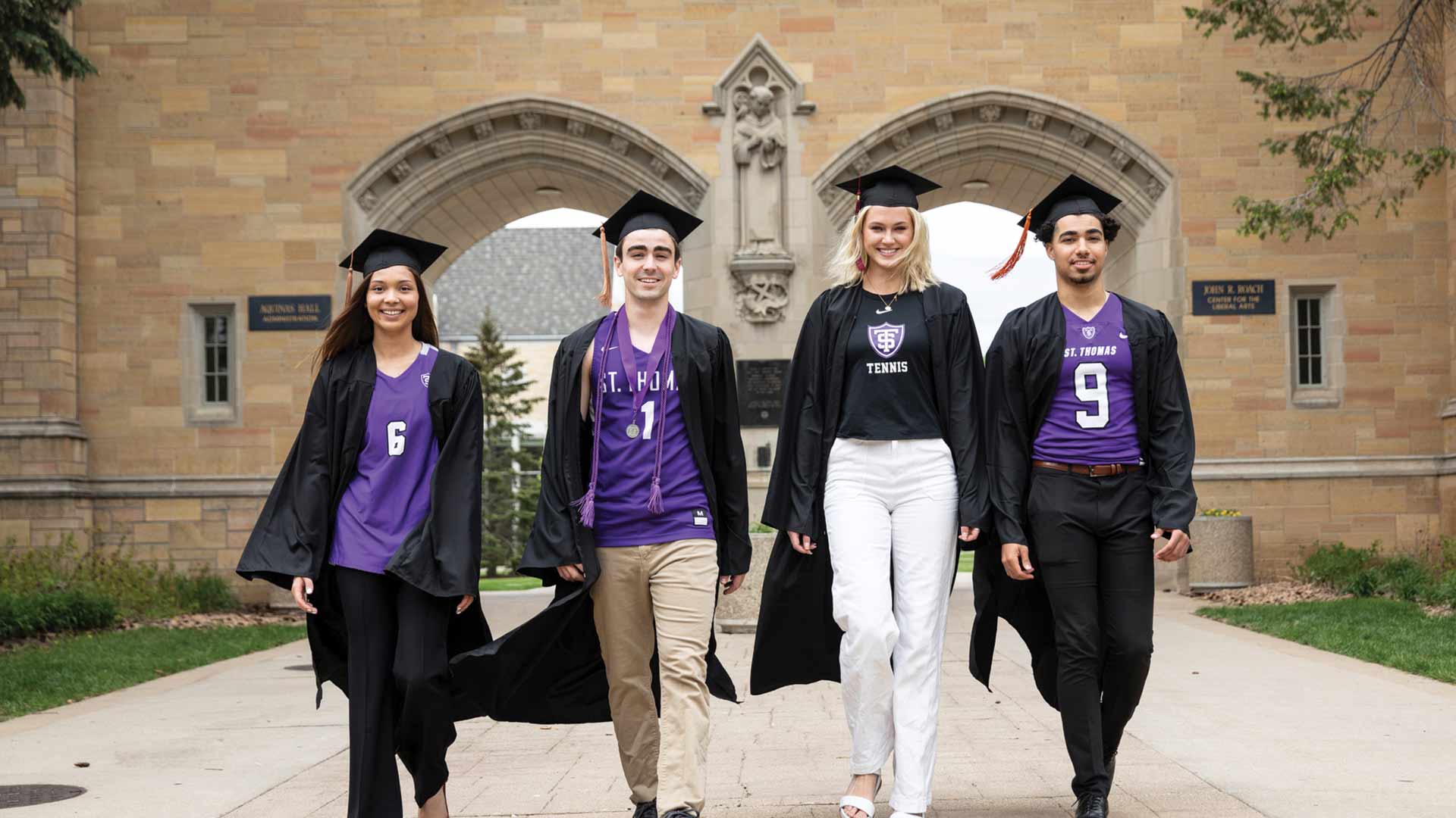 four students posing outside of arches on spring day